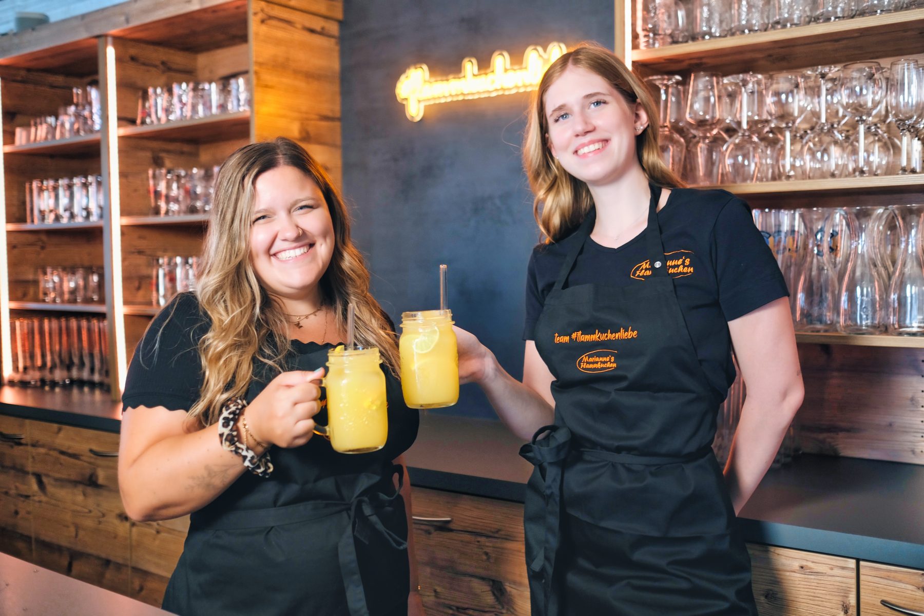 Zwei Mitarbeitende stoßen an der Theke mit hausgemachter Limonade an